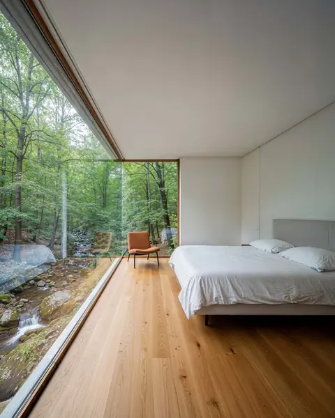 Bedroom with a glass wall onto the forest